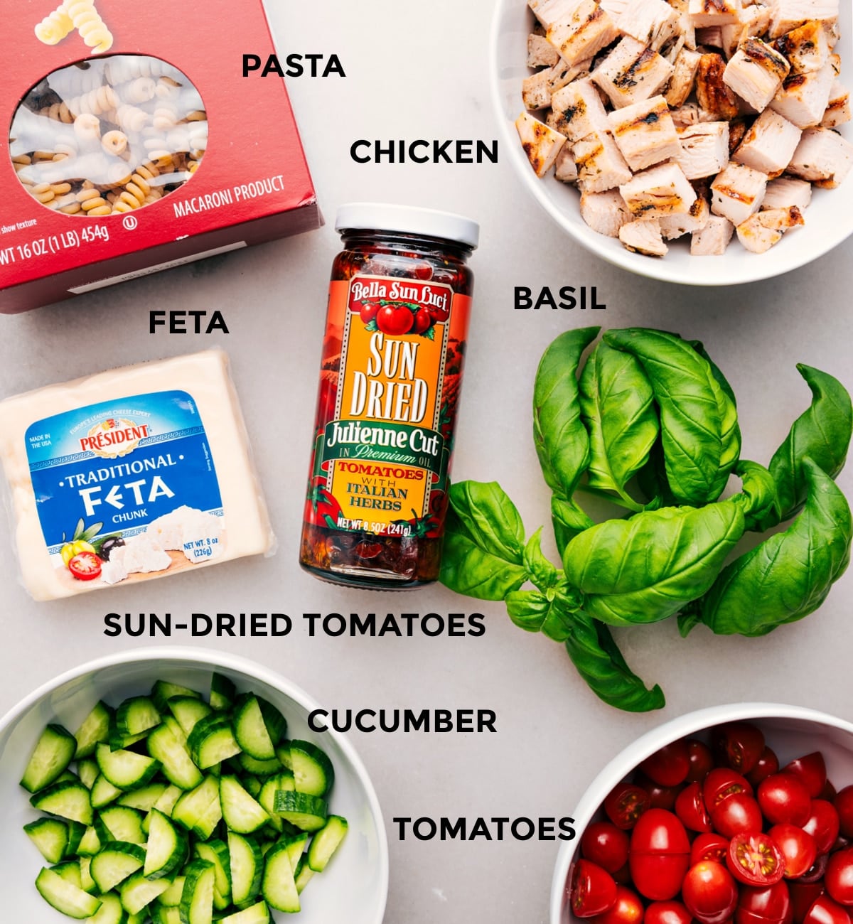 Ingredients In Marry Me Chicken Pasta Salad Everythingโs prepped for easy assemblyโpasta, chicken, basil, feta, sun-dried tomatoes, cucumber, and tomatoes.