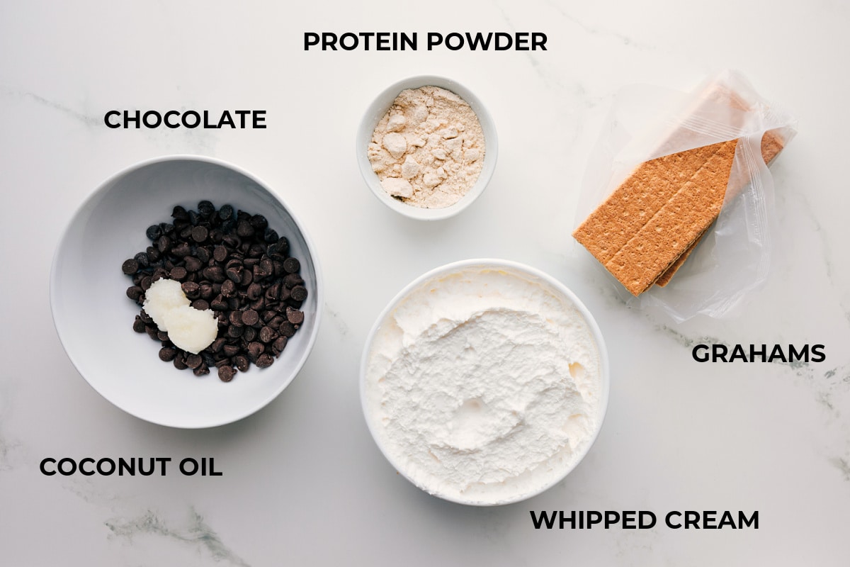 Ingredients In Frozen Protein S'mores All the ingredients prepped for easy assembly, including graham crackers, whipped cream, protein powder, chocolate, and coconut oil.