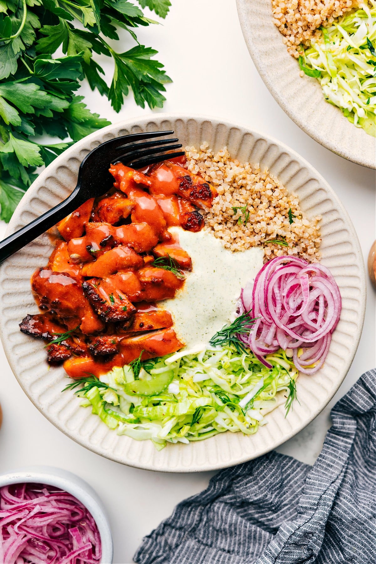 Flavorful And Delicious Buffalo Chicken Bowl Recipe Buffalo Chicken Bowl served over quinoa, topped with slaw, pickled red onions, and a creamy sauce.