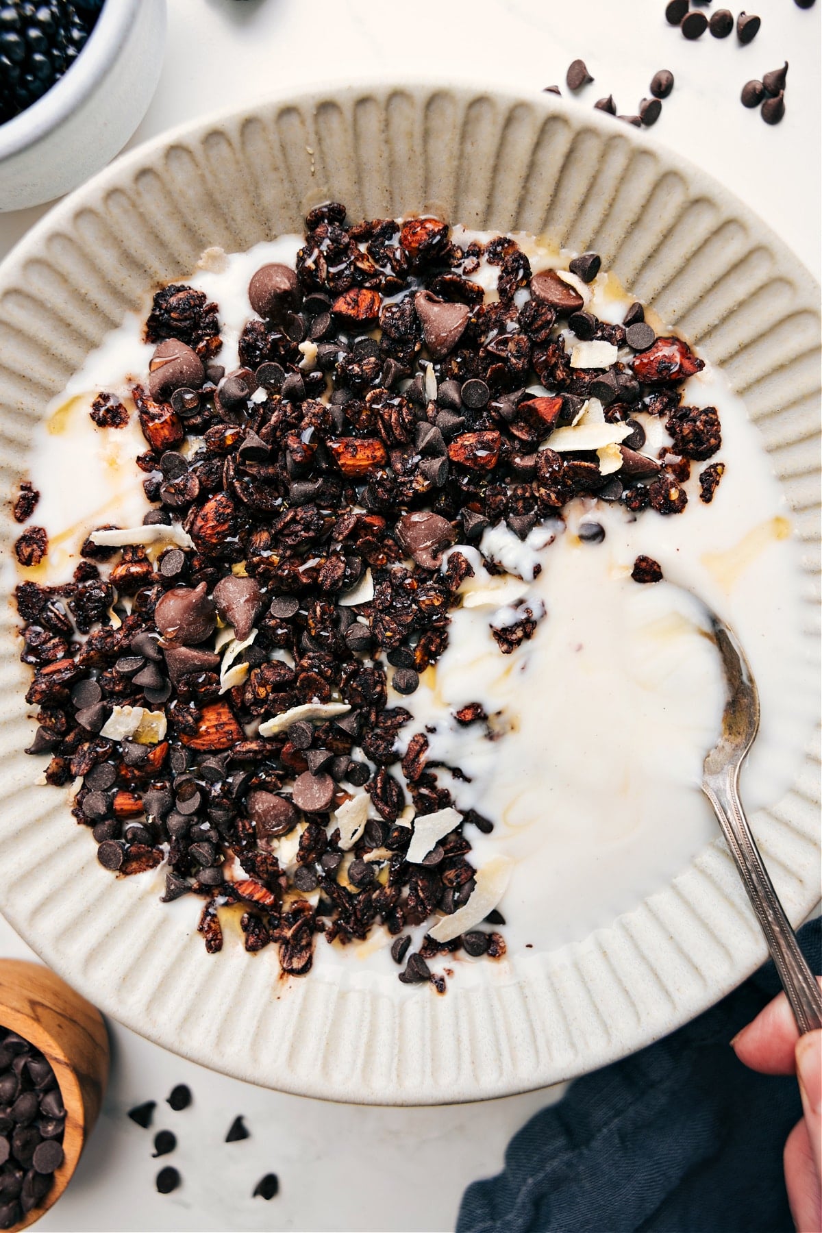 Chocolate granola served in a yogurt bowl with a drizzle of honey on top.