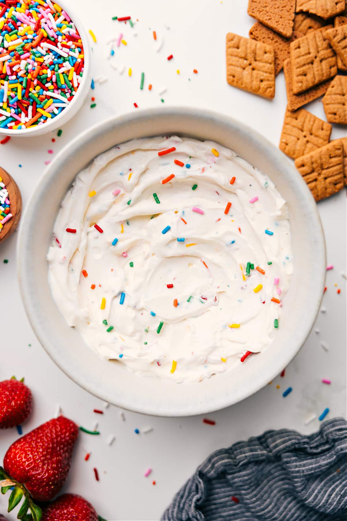 Fluffy yogurt in a bowl topped with colorful sprinkles, served with graham crackers on the side for dipping. A fun and high-protein treat.
