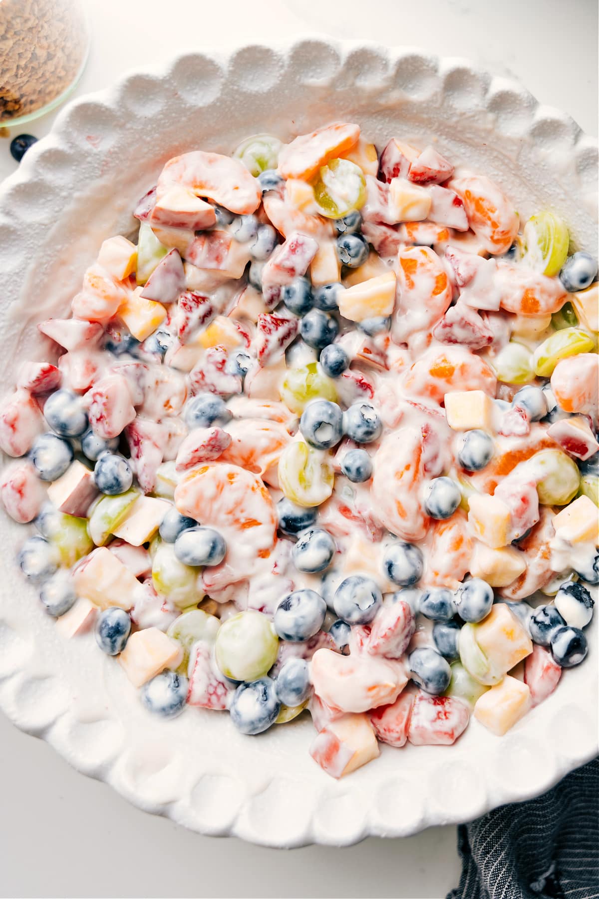 Fruit salad with creamy yogurt dressing mixed in a bowl, ready to serve and enjoy.