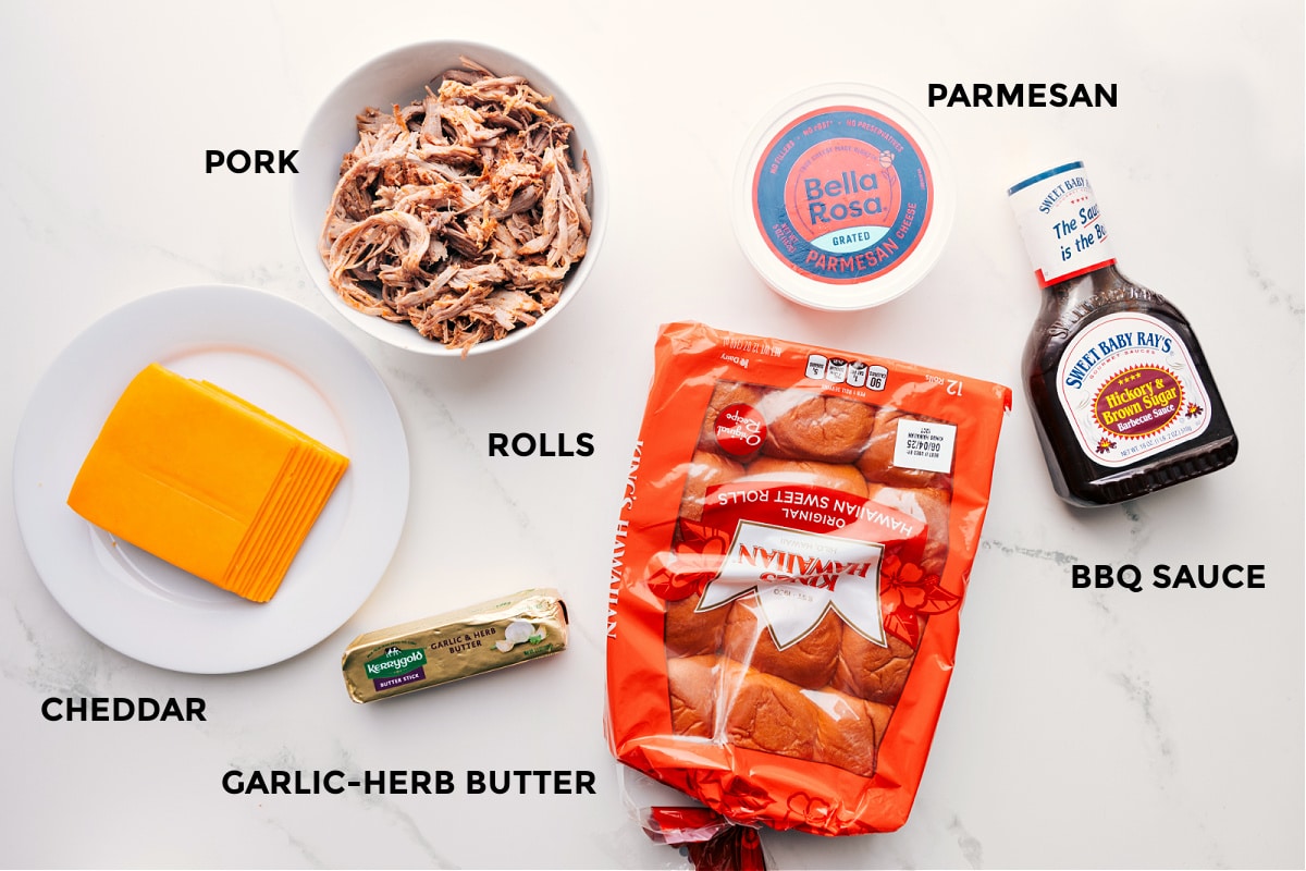 Ingredients In BBQ Pulled Pork Sliders All the ingredients prepped for easy assembly: cheddar, garlic-herb butter, Hawaiian rolls, pork, Parmesan, and BBQ sauce.