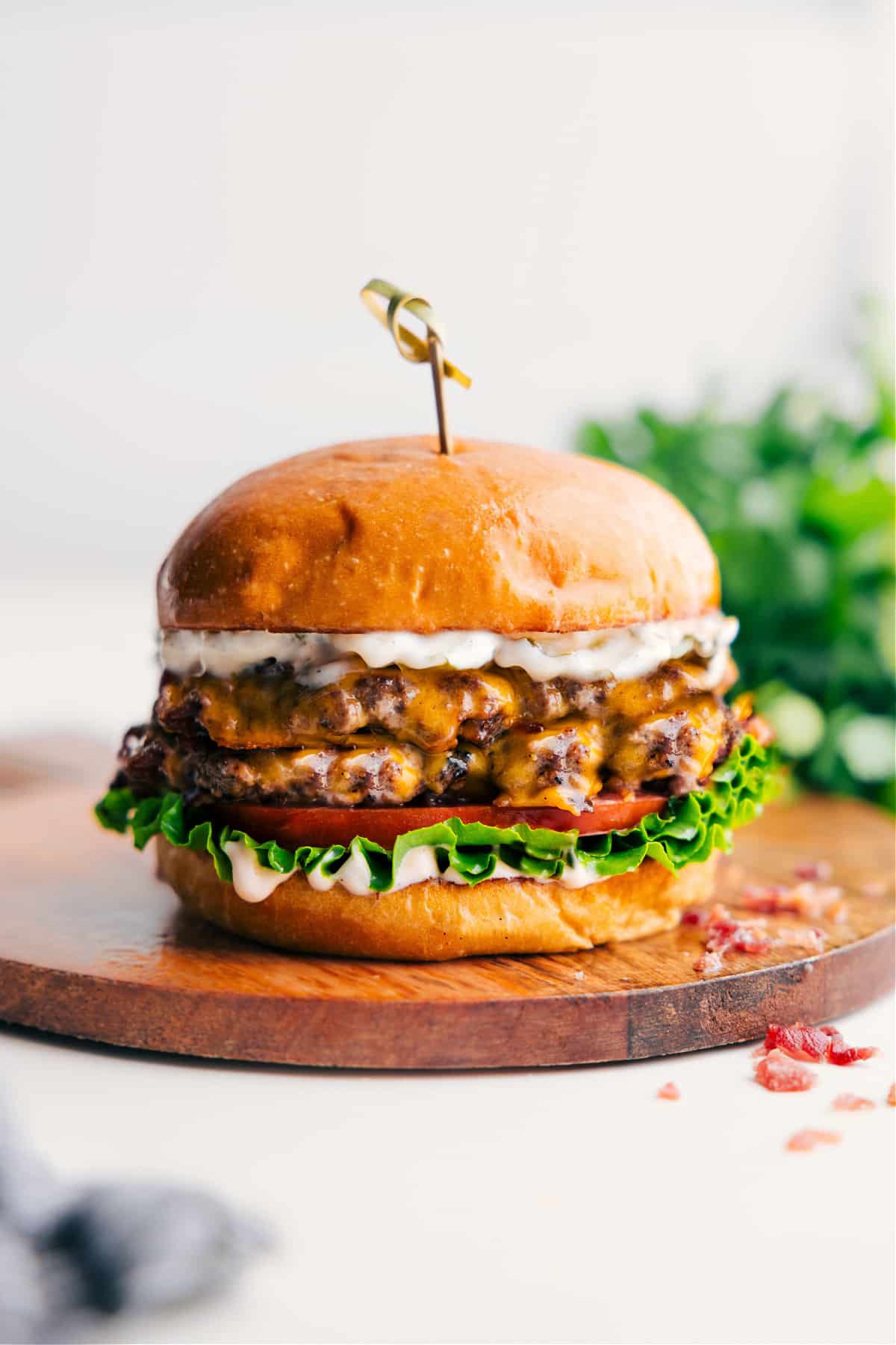 Crack Burger Recipe on a plate with melty cheese, tomatoes, lettuce, and creamy crack sauce.