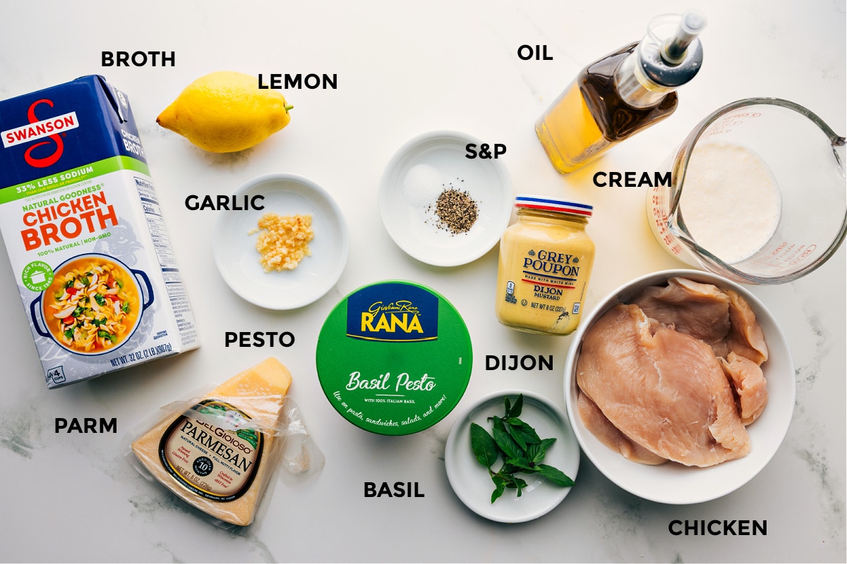 Ingredients In Creamy Pesto Chicken All the ingredients in this recipe prepped out for easy assembly including the broth, lemon, garlic, pesto, basil, basil, dijon, chicken, cream, and oil.