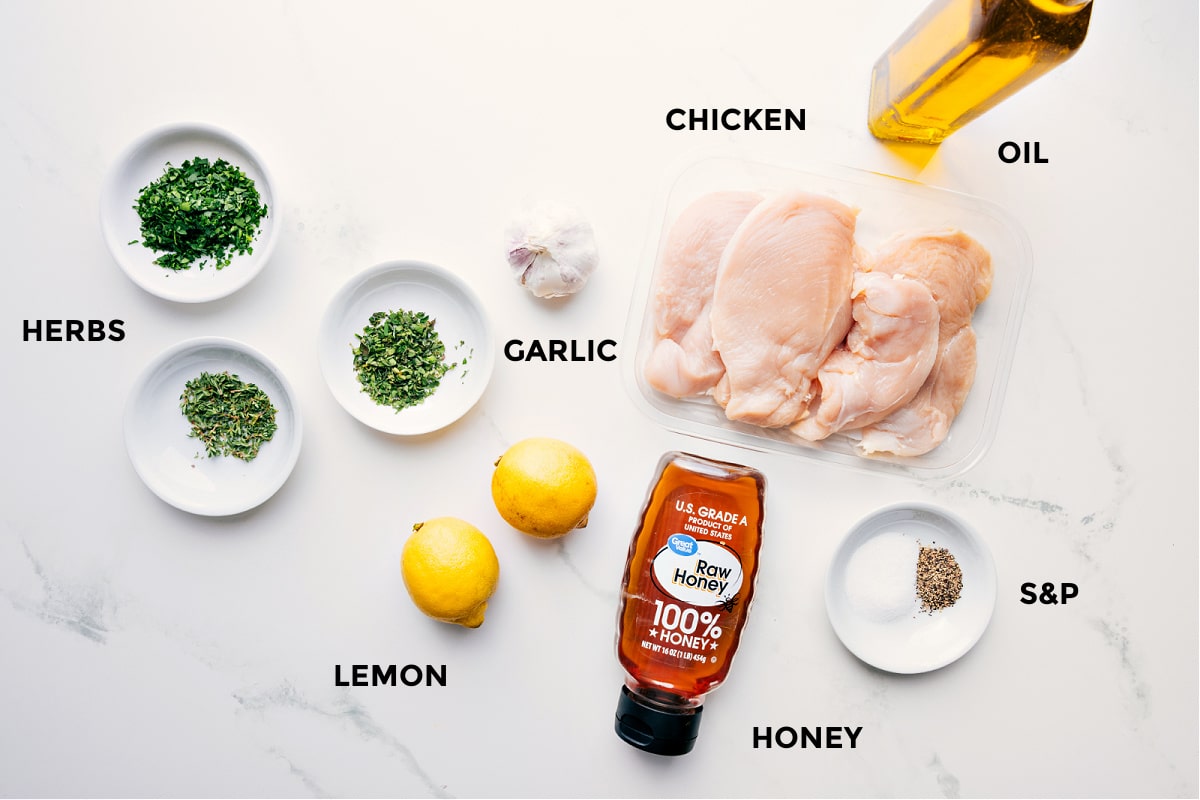 Ingredients In Greek Chicken Marinade All the ingredients in this recipe prepped out for easy assembly including the herbs, lemon, garlic, chicken, honey, and oil.