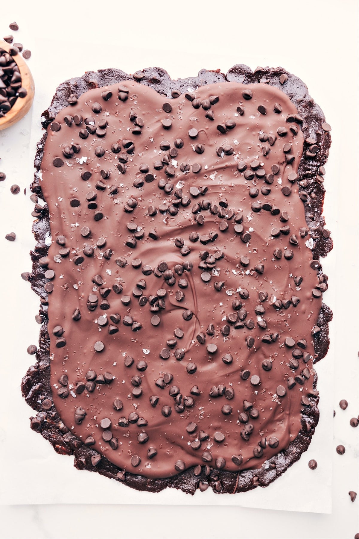 Healthy brownie batter bark with a thick layer of melted chocolate on top with more chocolate chips on top.