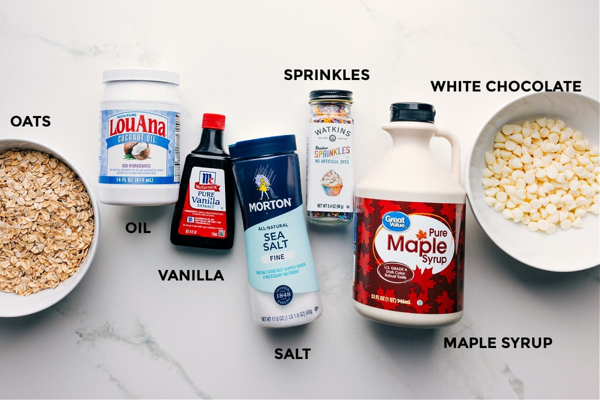 Ingredients In Healthy Cake Batter Bark Ingredients in this recipe prepped out for easy assembly including the oats, oil, vanilla, salt, sprinkles, maple syrup, and white chocolate.