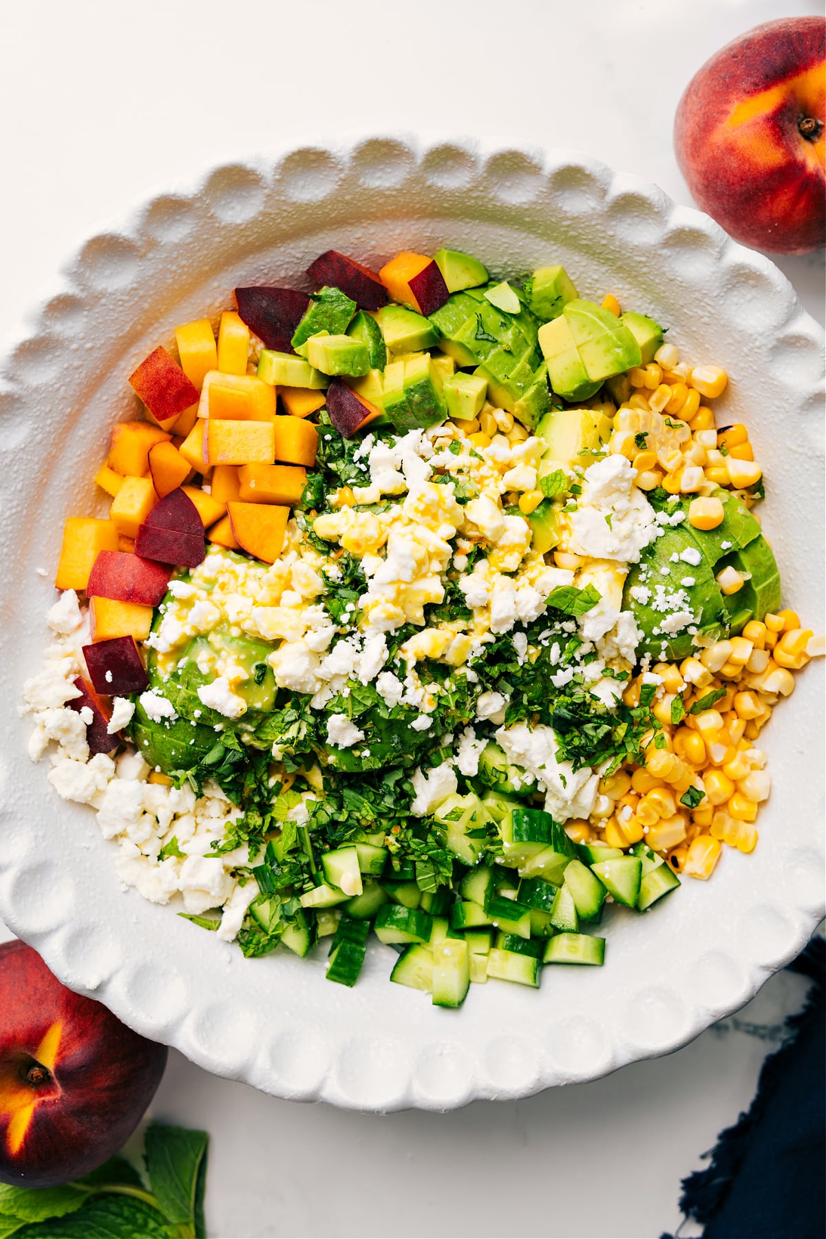 Peach Feta Salad Recipe Peach feta salad in a bowl drizzled with dressing ready to be tossed together and enjoyed.