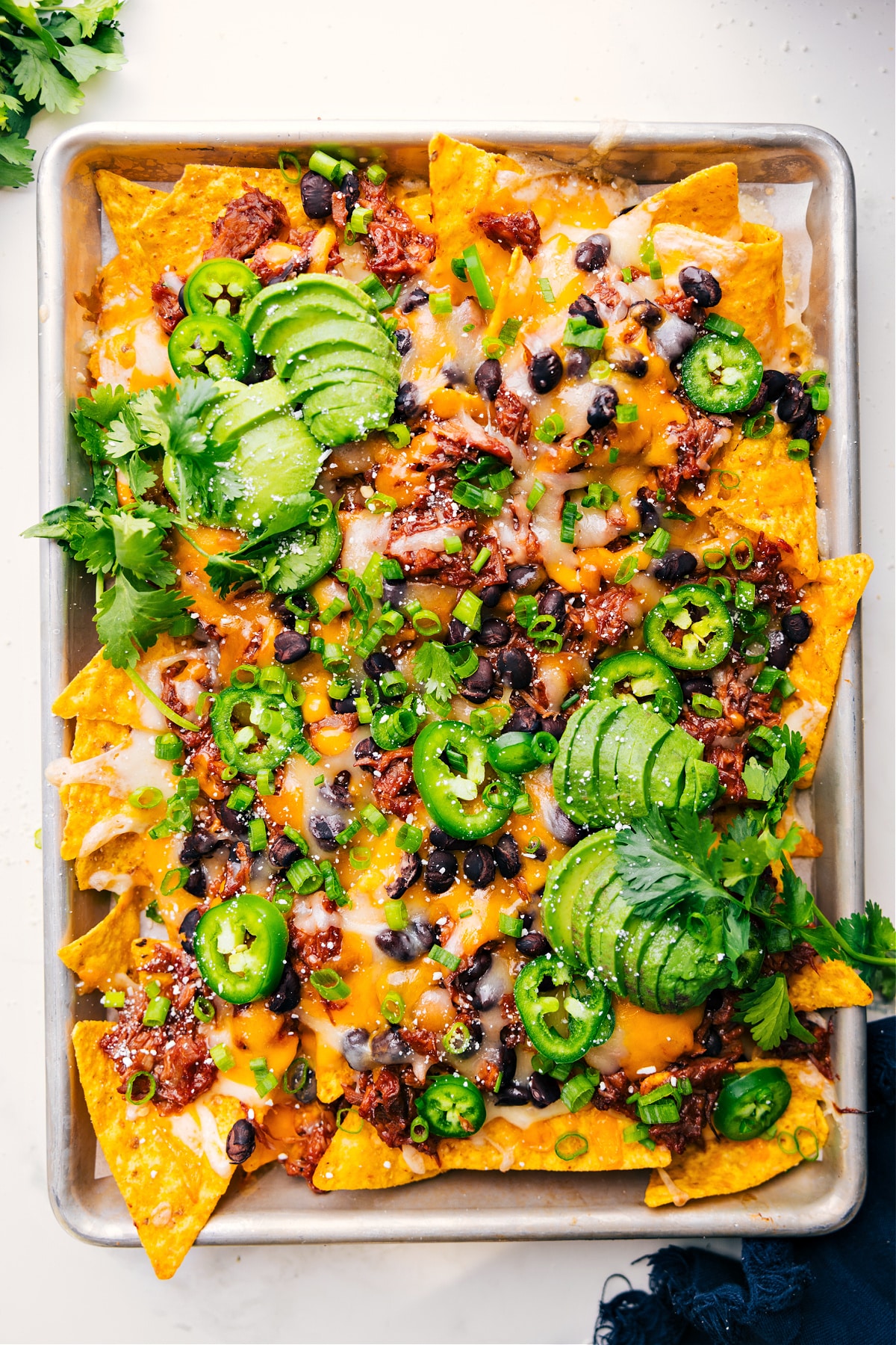 Freshly baked pulled pork nachos on a tray, hot and ready to eat.