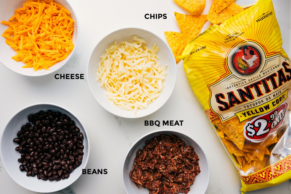 Ingredients in this recipe prepped out for easy assembly including the cheeses, beans, meat, and chips.