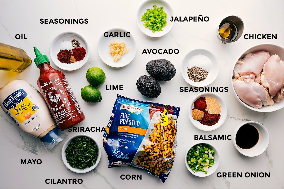 Ingredients In Street Corn Chicken Rice Bowl Ingredients in this recipe prepped out for easy assembly including the mayo, cilantro, seasonings, lime, garlic, jalapeno, balsamic, chicken, avocado, oil, green onions, and corn.