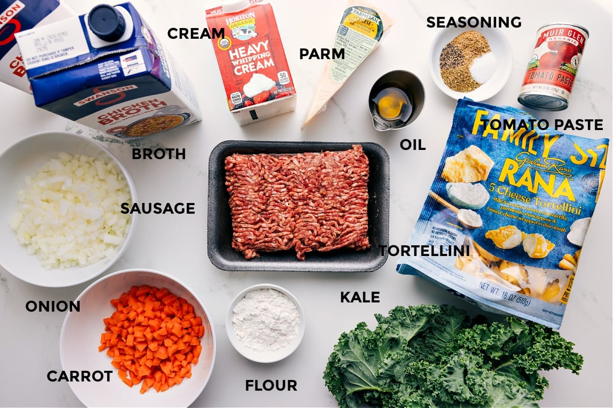 Ingredients In Crockpot Tortellini Soup All the ingredients prepped for easy assembly, including broth, sausage, onion, carrot, cream, flour, Parmesan, oil, tortellini, kale, seasonings, and tomato paste.