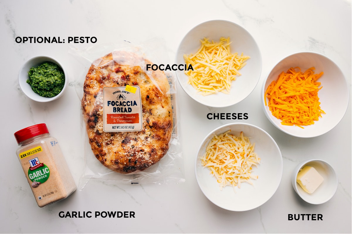 Ingredients In Focaccia Grilled Cheese Ingredients laid out for easy assembly: bread, cheeses, butter, garlic powder, and optional pesto.