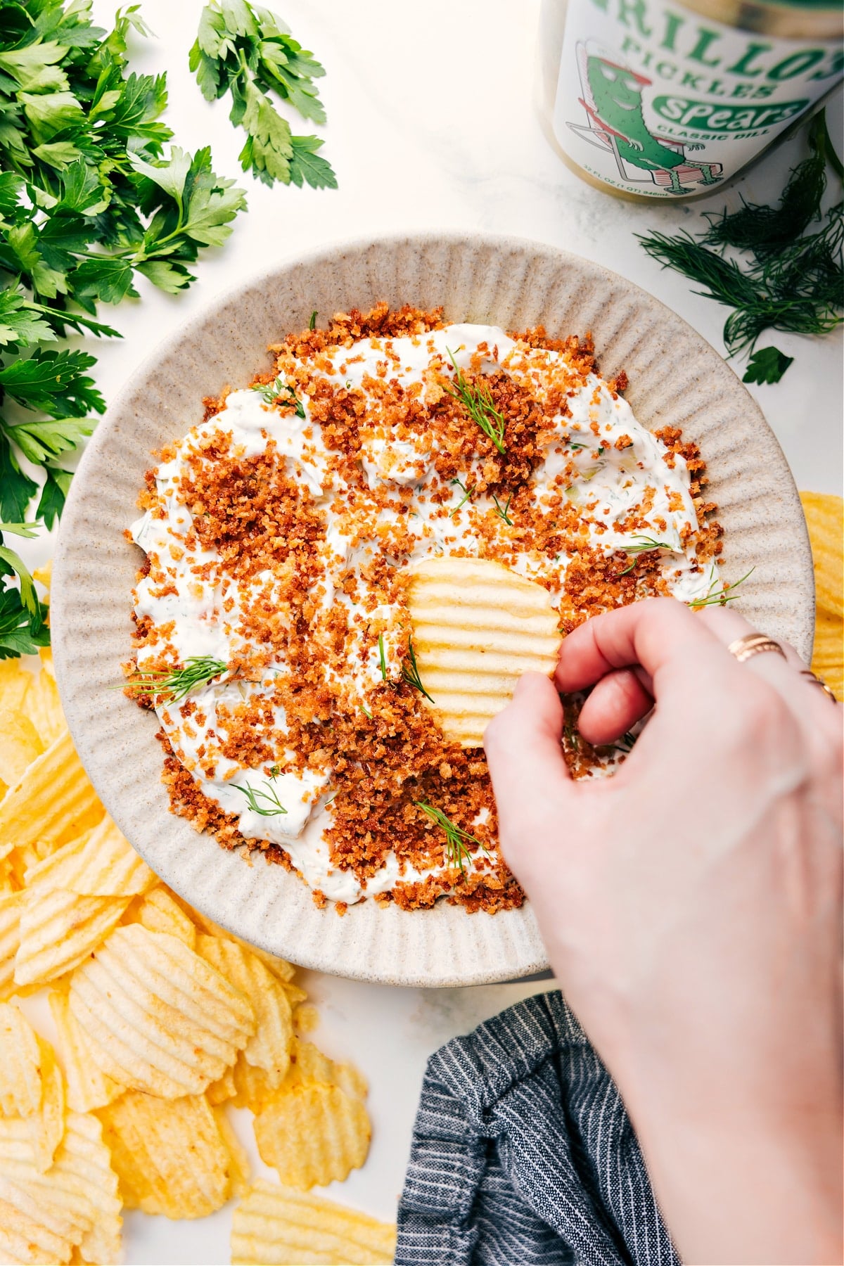Bowl of Fried Pickle Dip with a chip scooping a bite.