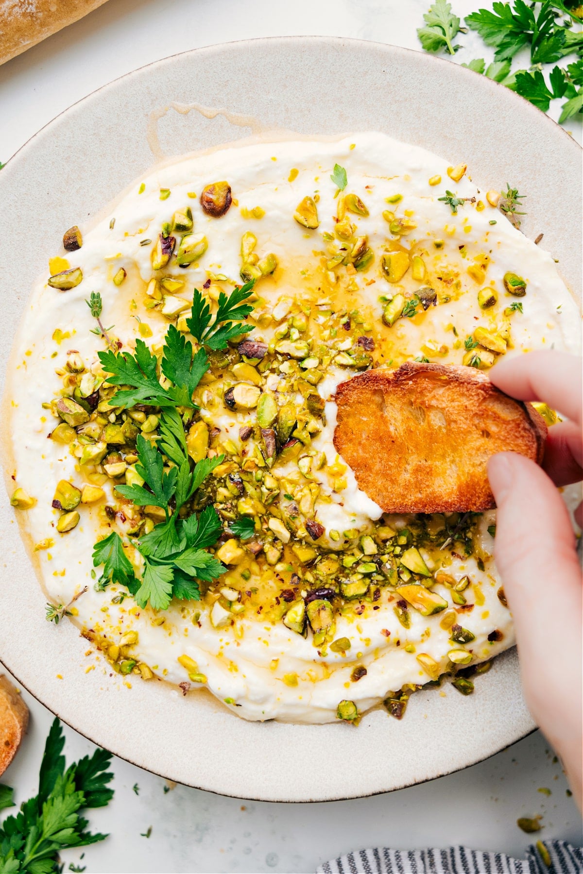 Whipped Feta Recipe Greek recipes: Whipped feta recipe with pistachios on top with a piece of bread dipping in.