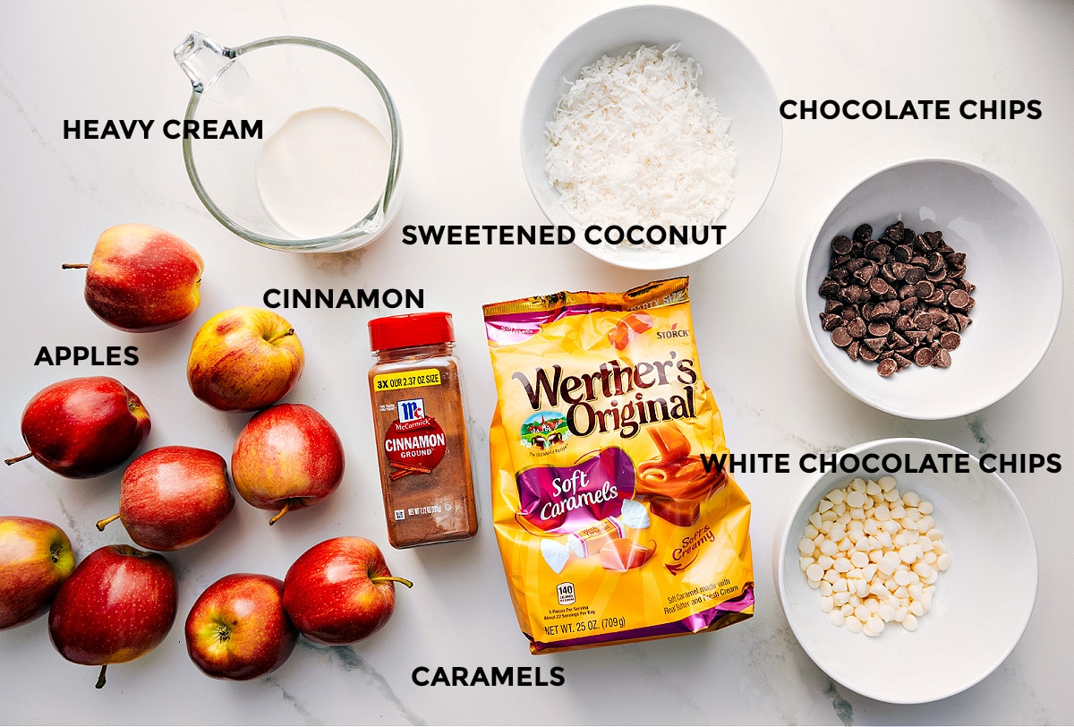Ingredients In Caramel Apple Dessert Cups All the ingredients prepped and ready to assemble, including apples, heavy cream, cinnamon, sweetened coconut, caramels, chocolate chips, and white chocolate chips.
