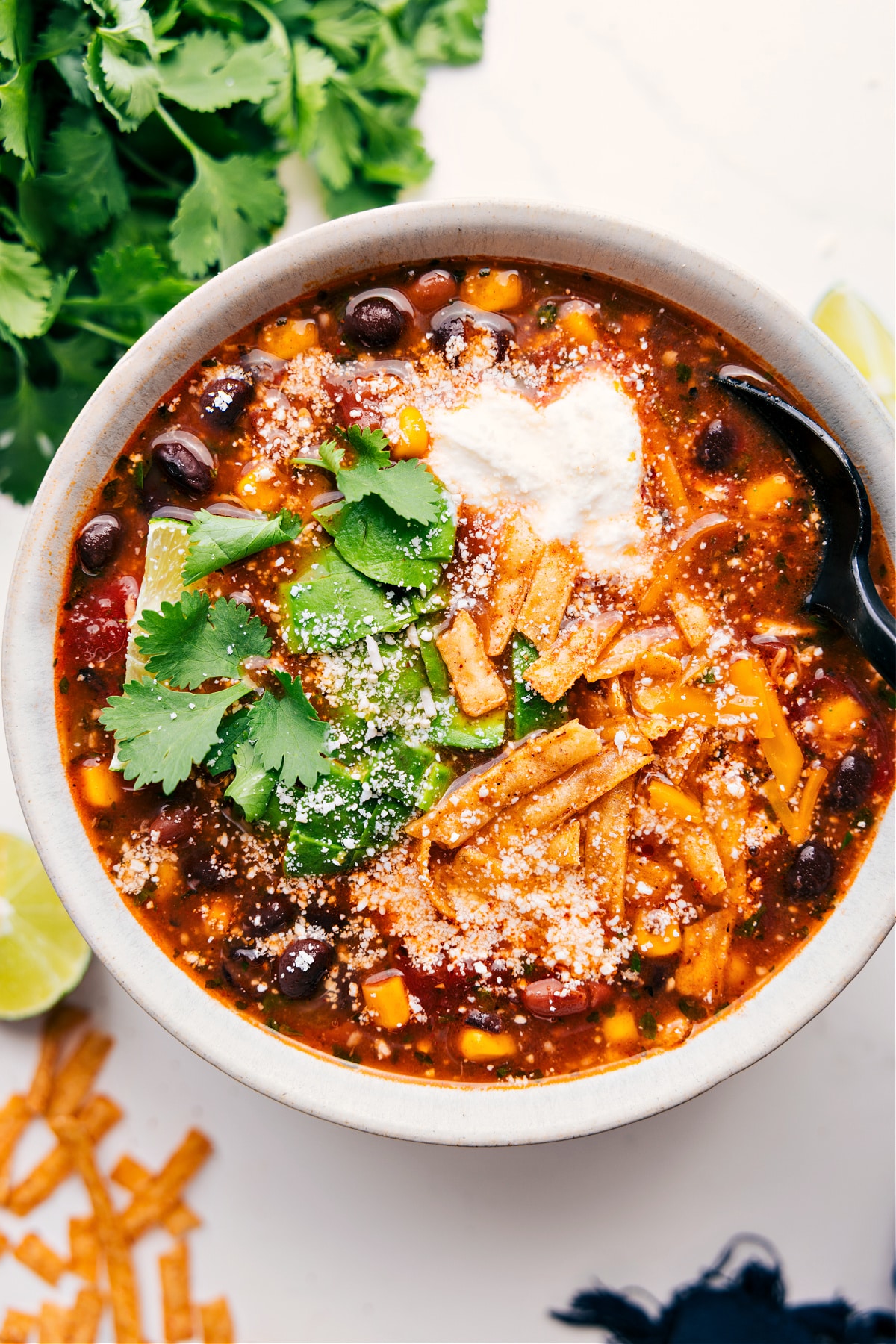 The Best Chicken Taco Soup With Delicious Toppings The soup in a bowl with all the best toppings including cilantro, tortilla strips, sour cream, and cheese.