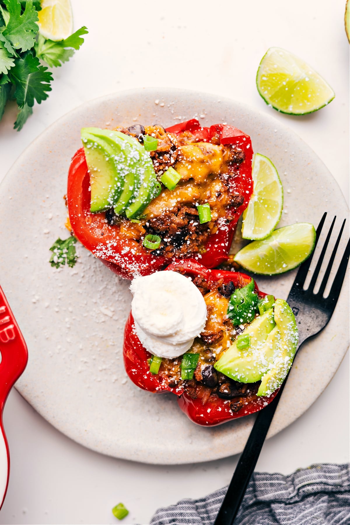 Mexican Stuffed Peppers With All The Yummy Toppings Stuffed pepper cut in half, topped with sour cream, avocado, cilantro, and jalapeños, ready to eat.