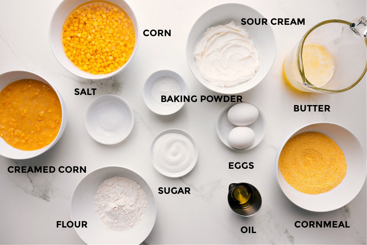 Ingredients In Corn Pudding Recipe All the ingredients in this recipe prepped out for easy assembly including the creamed corn, corn, salt, flour, baking powder, sugar, sour cream, eggs, oil, cornmeal, and butter.