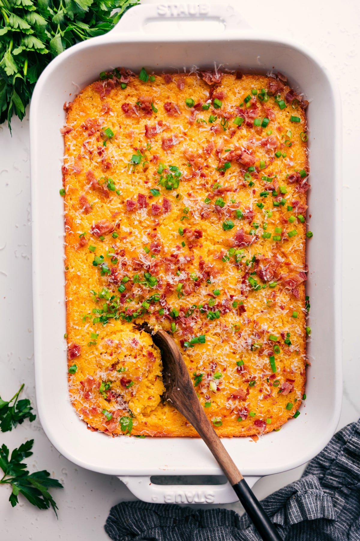 Corn Pudding Casserole in the casserole dish topped with cheese, green onions, and bacon.