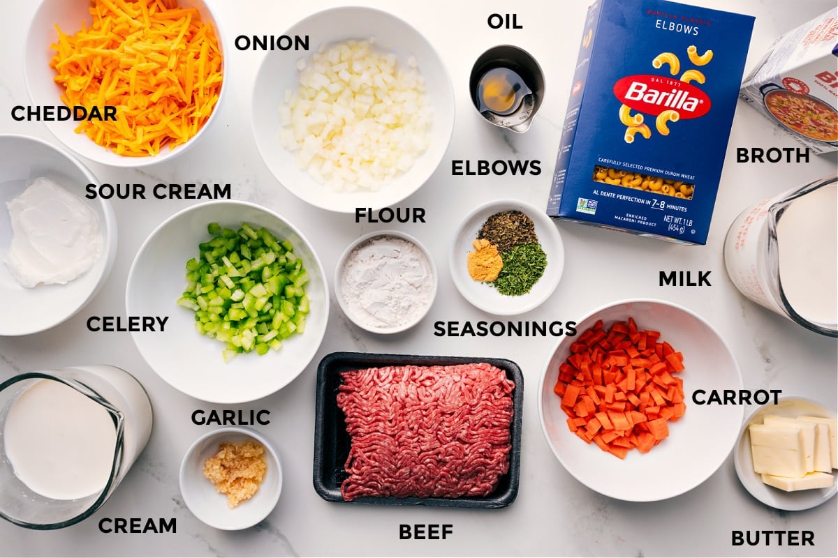 Ingredients In Cheeseburger Macaroni Soup All the ingredients for this recipe prepped and ready for easy assembly, including sour cream, cream, cheddar, onion, celery, garlic, flour, ground beef, seasonings, oil, carrot, milk, butter, pasta, and broth.