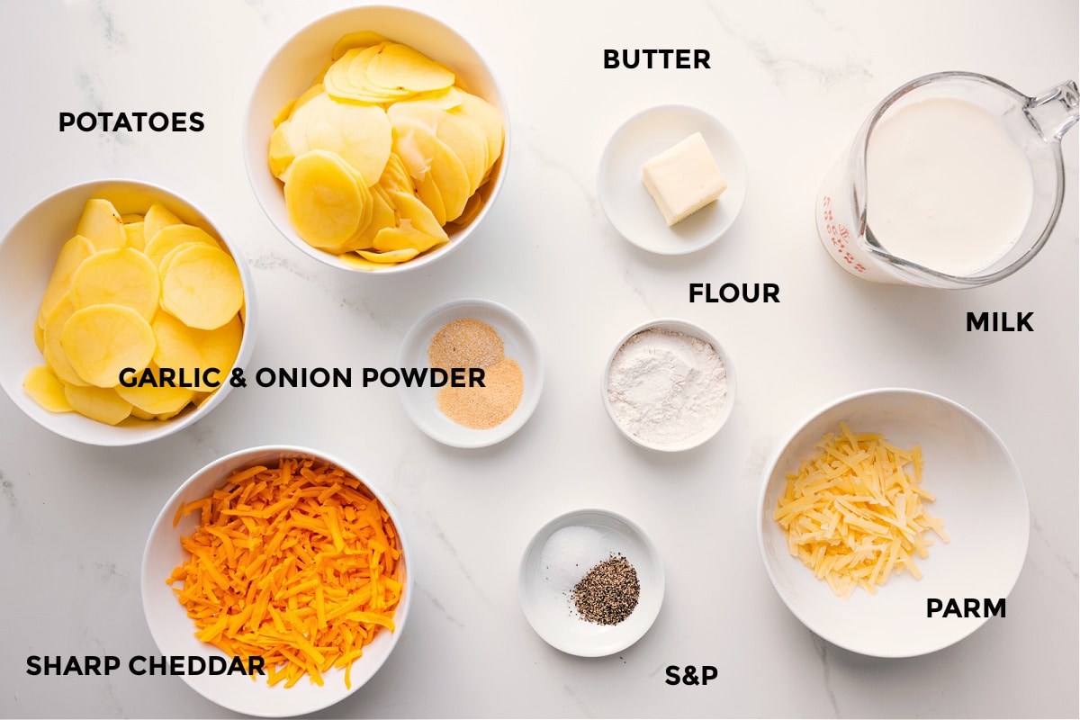 Ingredients In Cheesy Scalloped Potatoes All the ingredients in this recipe prepped out for easy assembly including the potatoes, cheese, seasonings, flour, butter, parm, and milk.