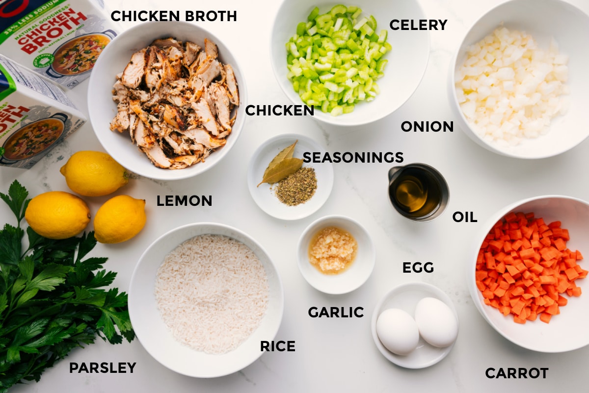 Ingredients In Greek Lemon Soup Prepped ingredients including broth, lemon, parsley, rice, chicken, spices, celery, onion, carrot, oil, egg, and garlic.