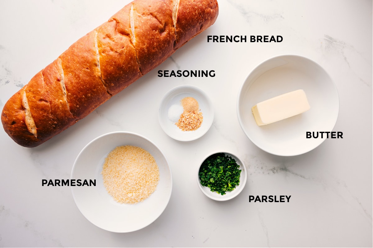 Ingredients In Garlic Bread Recipe All the ingredients in this recipe prepped out for easy assembly including French bread, parmesan, seasoning, parsley, and butter.