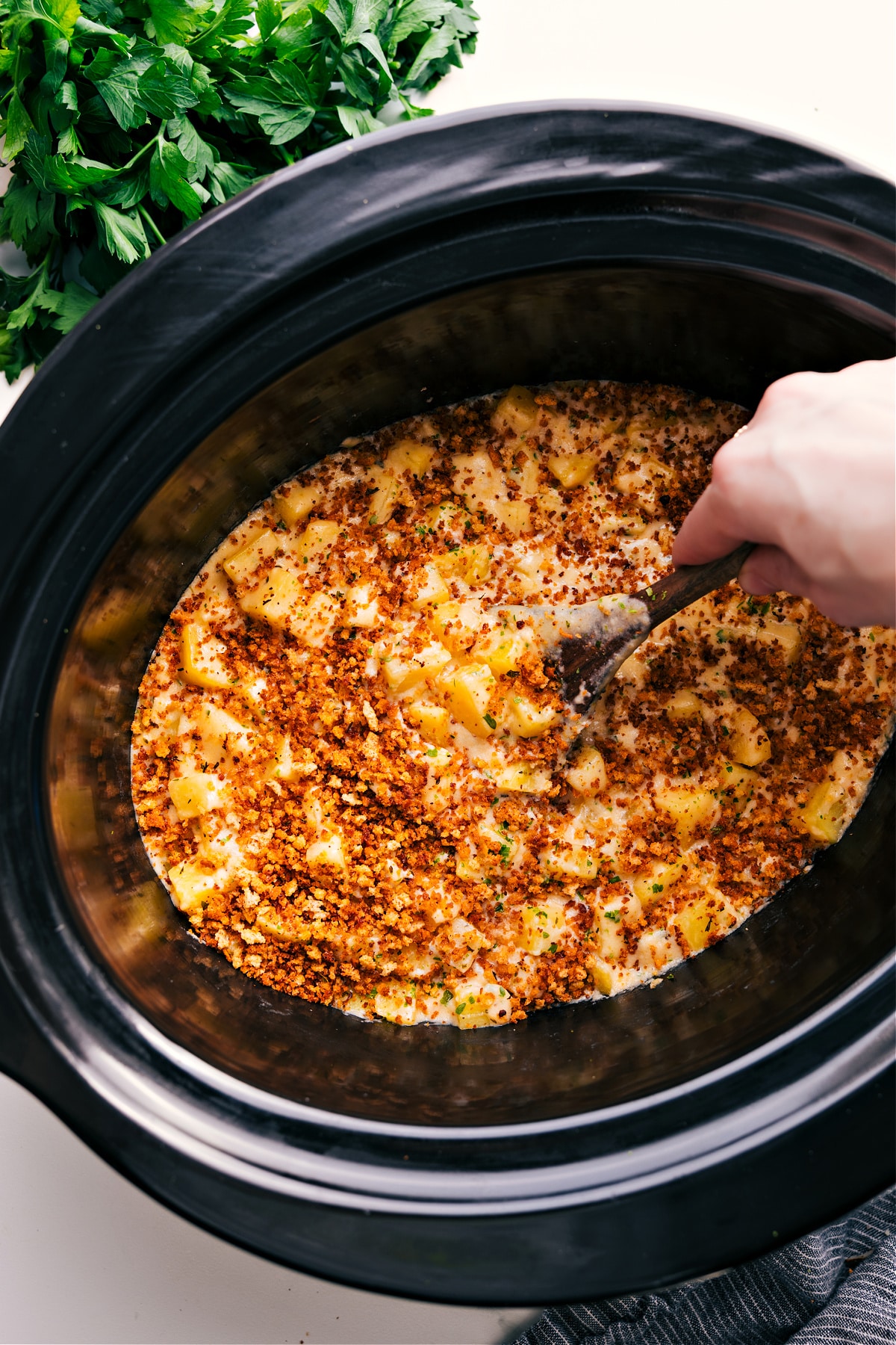 Crockpot Cheesy Potatoes in the slow cooker with a big spoonful coming out.
