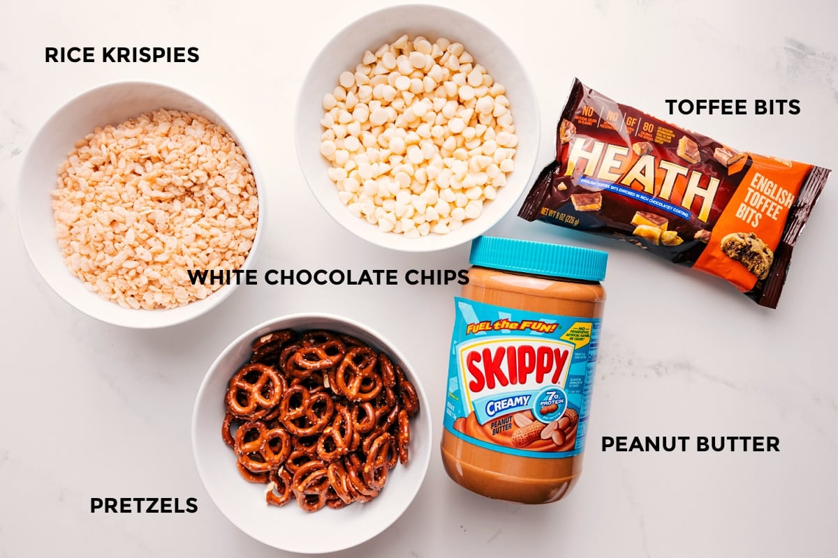 All the ingredients in this recipe prepped out for easy assembly including the rice krispies, pretzels, white chocolate chips, peanut butter, and toffee bits.