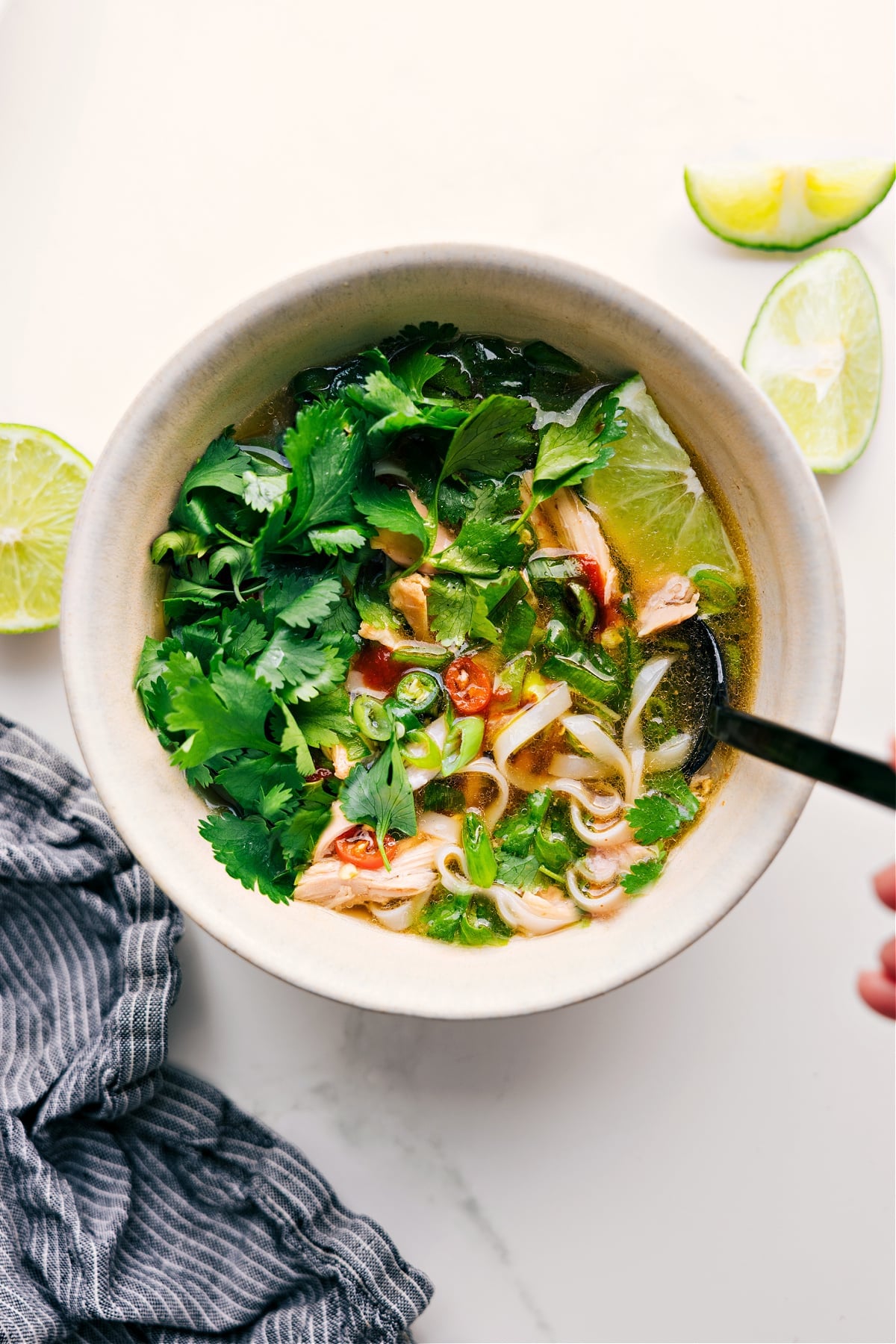 Chicken Pho Recipe in a bowl with fresh cilantro, lime, and peppers on top.