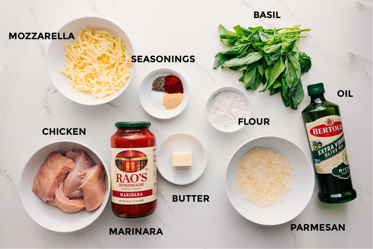 Ingredients In Parmesan Chicken Recipe Ingredients in this recipe prepped out for easy assembly including the mozzarella, chicken, seasoning, marinara, butter, flour, parmesan, basil, and oil.