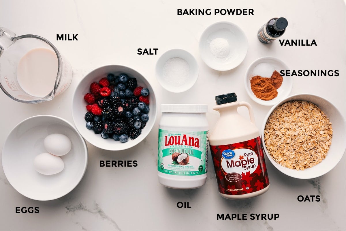 Ingredients In Berry Oatmeal Bake Recipe Ingredients in this recipe prepped out for easy assembly including the milk, eggs, berries, salt, oil, maple syrup, oats, seasonings, vanilla, and baking powder.