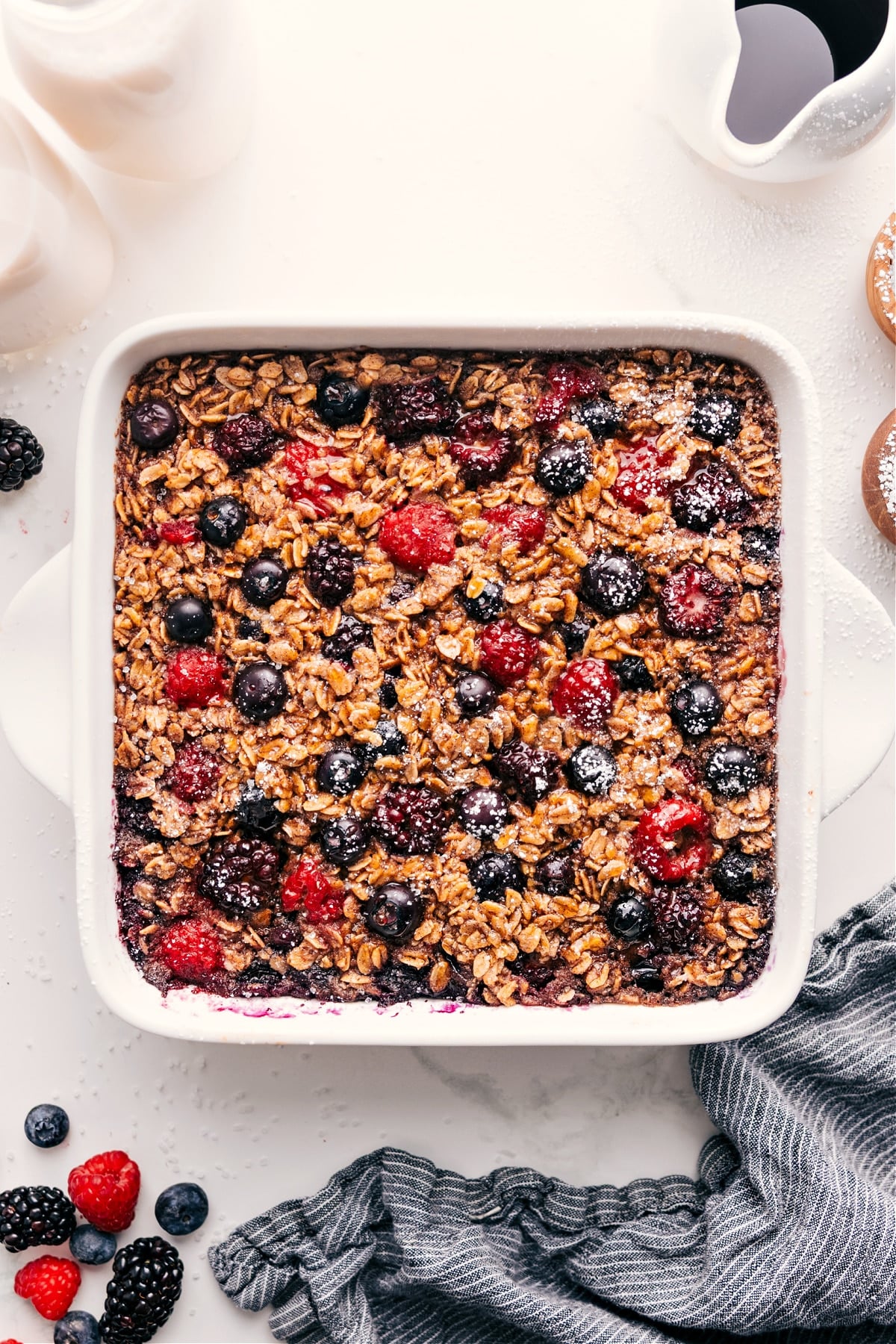 Berry oatmeal bake in the pan with powdered sugar sprinkled on top.