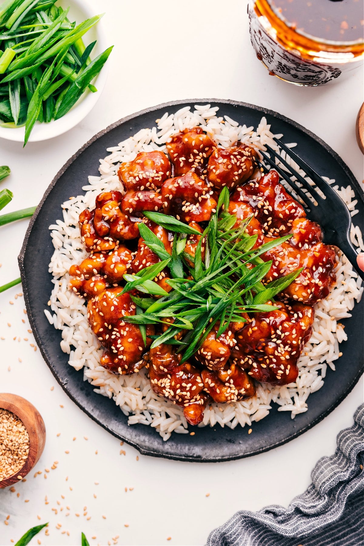 Korean Chicken Recipe on a bed of rice with fresh green onions and sesame seeds on top.