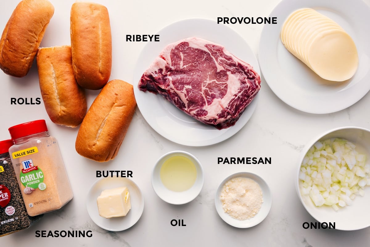 Ingredients In Philly Cheesesteak Recipe All the ingredients in this recipe prepped out for easy assembly including the rolls, seasonings, butter, oil, parmesan, ribeye, provolone, and onions.