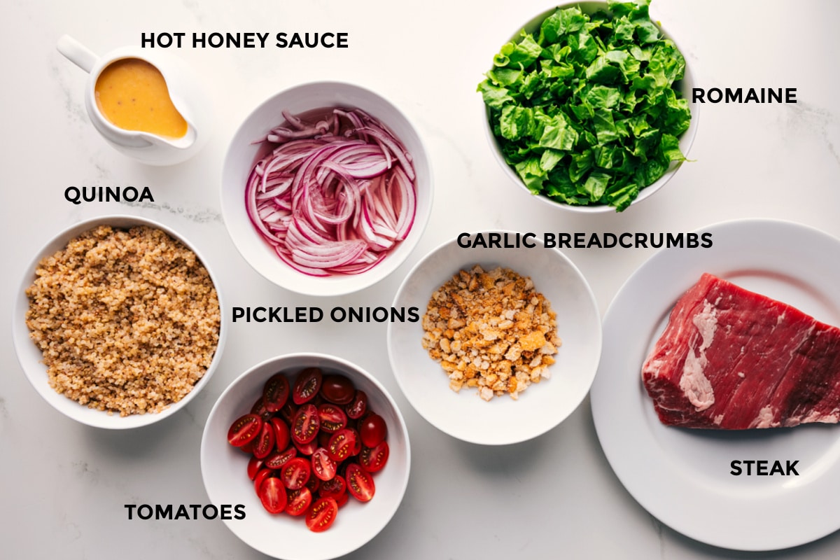 Ingredients In This Steak Bowl Recipe All the ingredients in this recipe prepped out for easy assembly including the hot honey sauce, quinoa, tomatoes, pickled onions, romaine, garlic breadcrumbs, and steak.