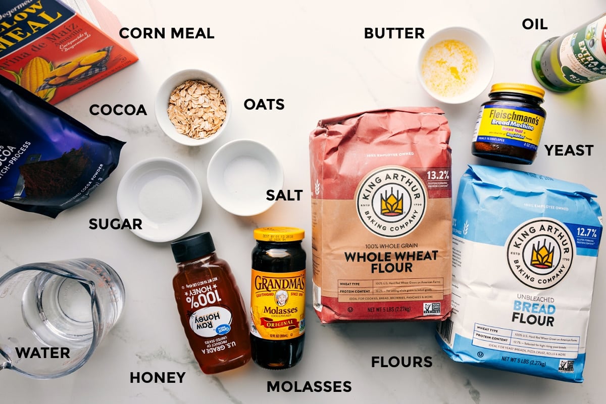 Ingredients In Brown Bread Recipe All the ingredients in this recipe prepped out for easy assembly including the corn meal, cocoa. sugar, water, honey, molasses, salt, oats, flours, yeast, butter, and oil.