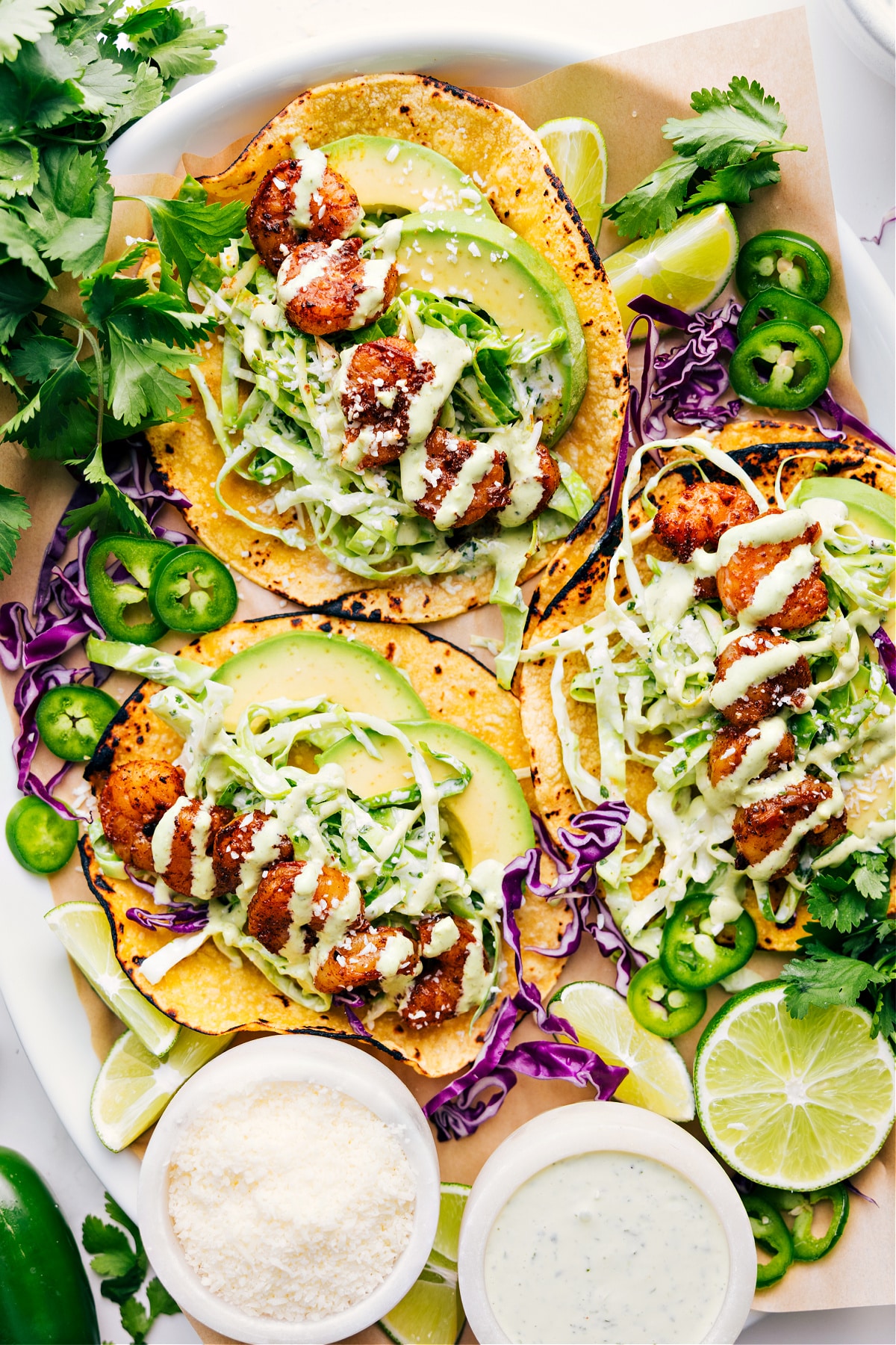 Shrimp tacos on a platter topped with cilantro lime sauce and cotija cheese.