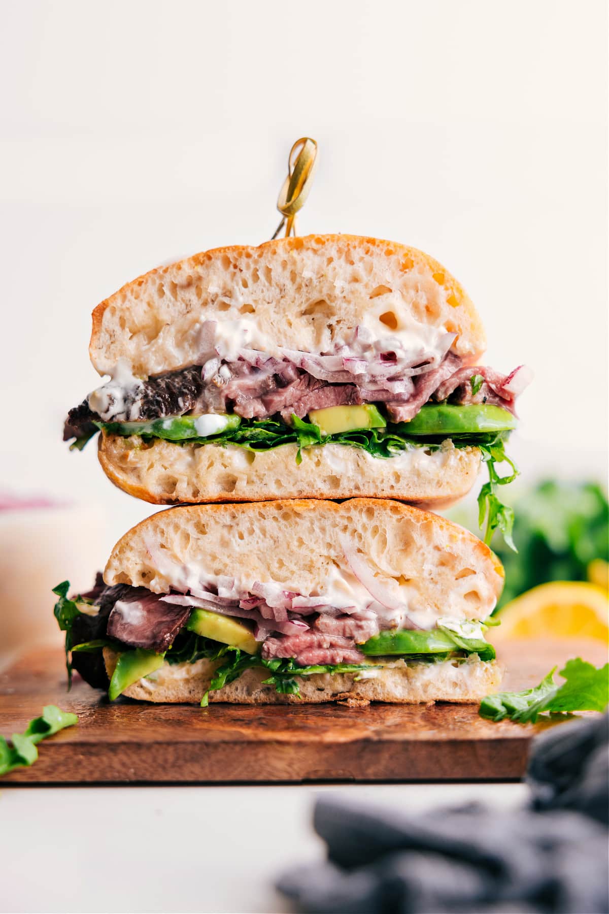 Steak Sandwich Recipe stacked on top of each other with avocado, lettuce, and aioli sauce.