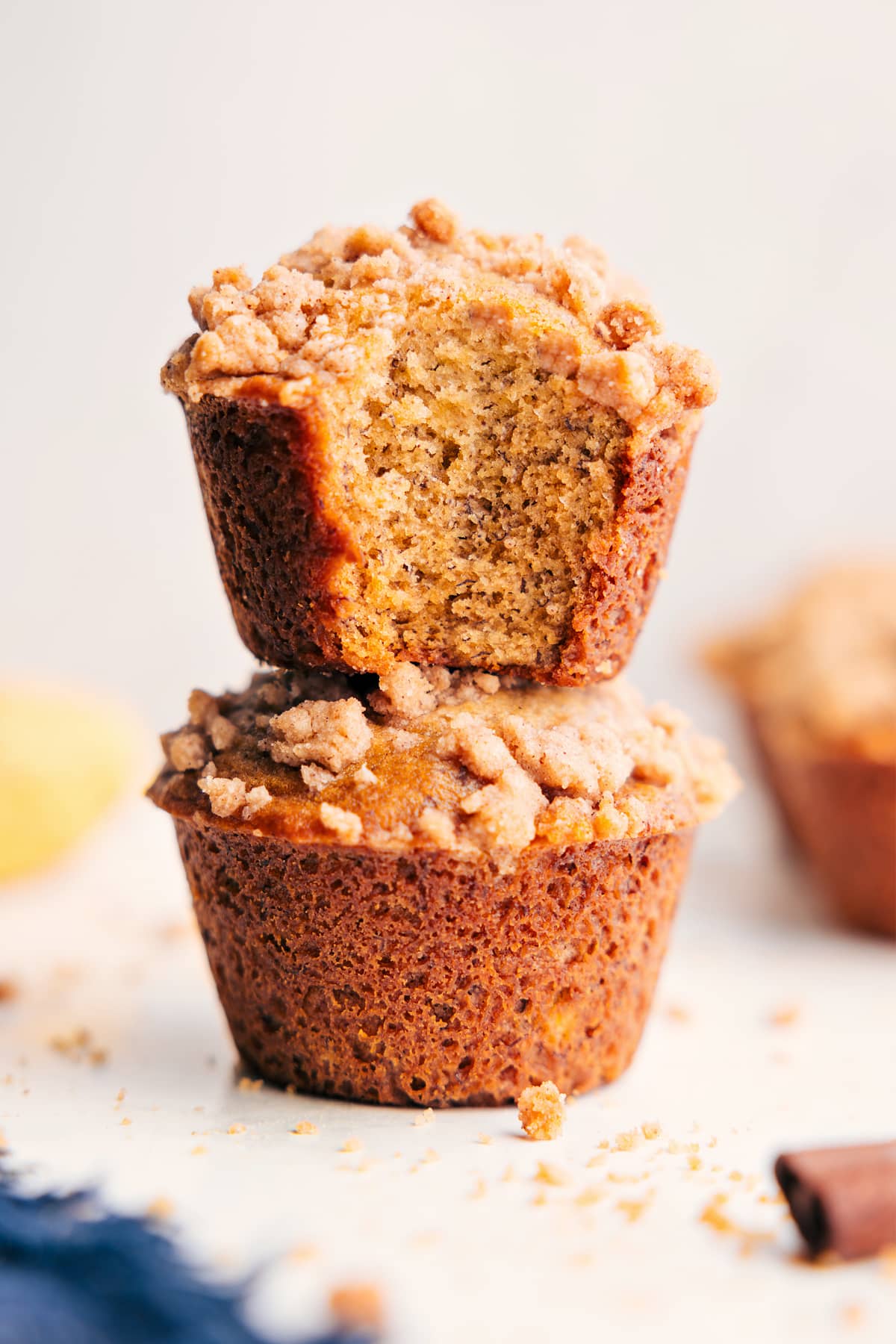 Banana crumb muffins stacked with a bite taken out, showing the soft inside and crumb topping.