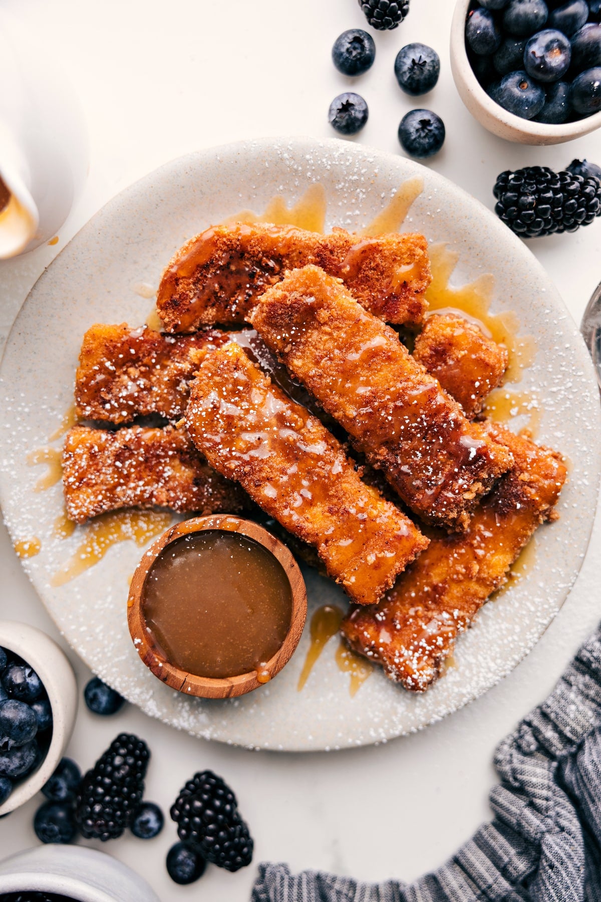 French Toast Sticks Recipe served on a plate with maple syrup and powdered sugar.