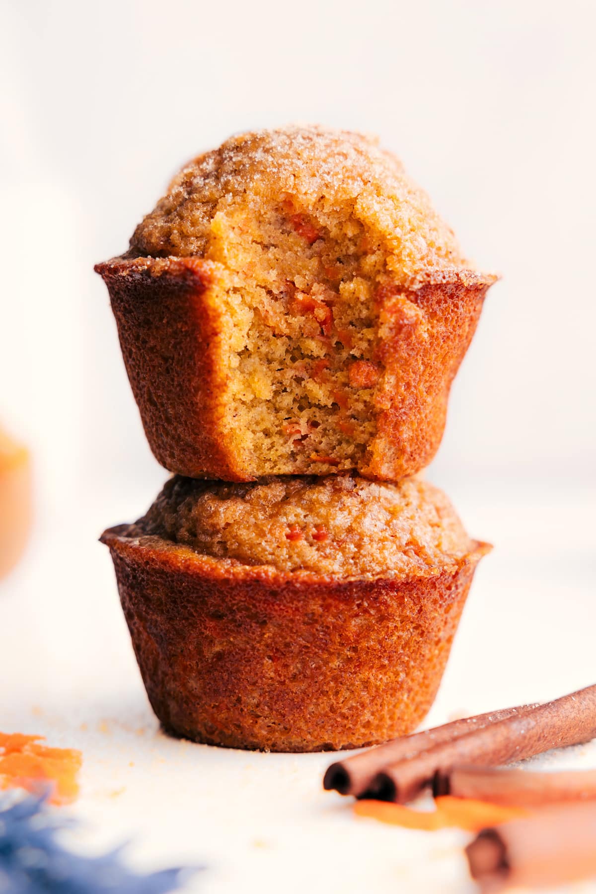 Healthy Carrot Muffins stacked with a bite taken out of the top muffin, showing the soft, tender inside.