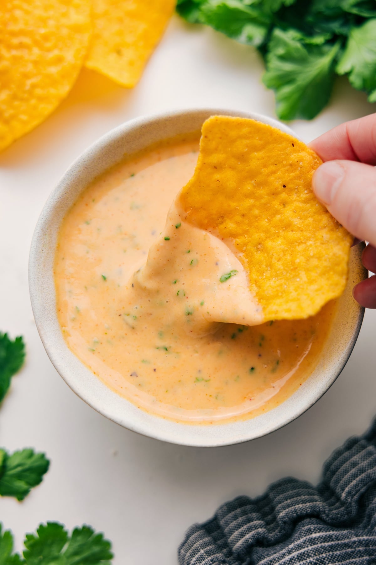 Queso dip in a bowl with a tortilla chip dipping into the melted cheese.