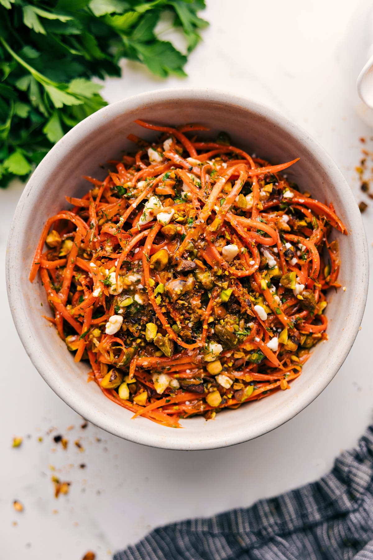 Fresh And Flavorful Ribbon Carrot Salad Ribbon carrot salad in a bowl tossed with dressing and topped with pistachios and fresh herbs.