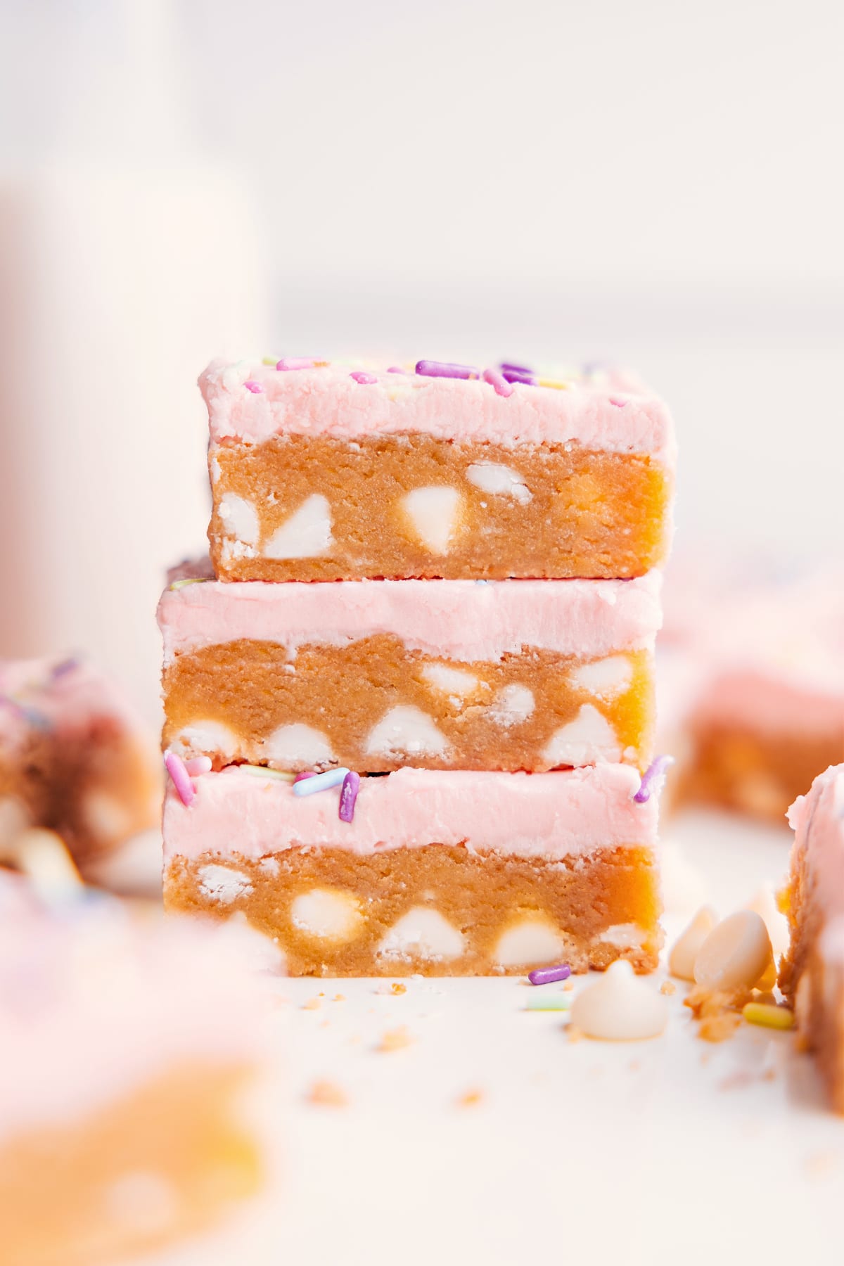 Sugar Cookie Bars Recipe stacked with white chocolate chips in the bars and creamy frosting on top.