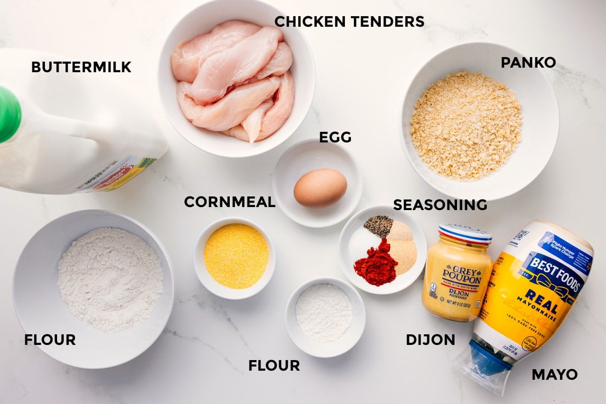 Ingredients In Baked Chicken Tenders All the ingredients in this recipe prepped out for easy assembly including buttermilk, flour, cornmeal, flour, meat, egg, flour, seasoning, dijon, mayo, and panko.