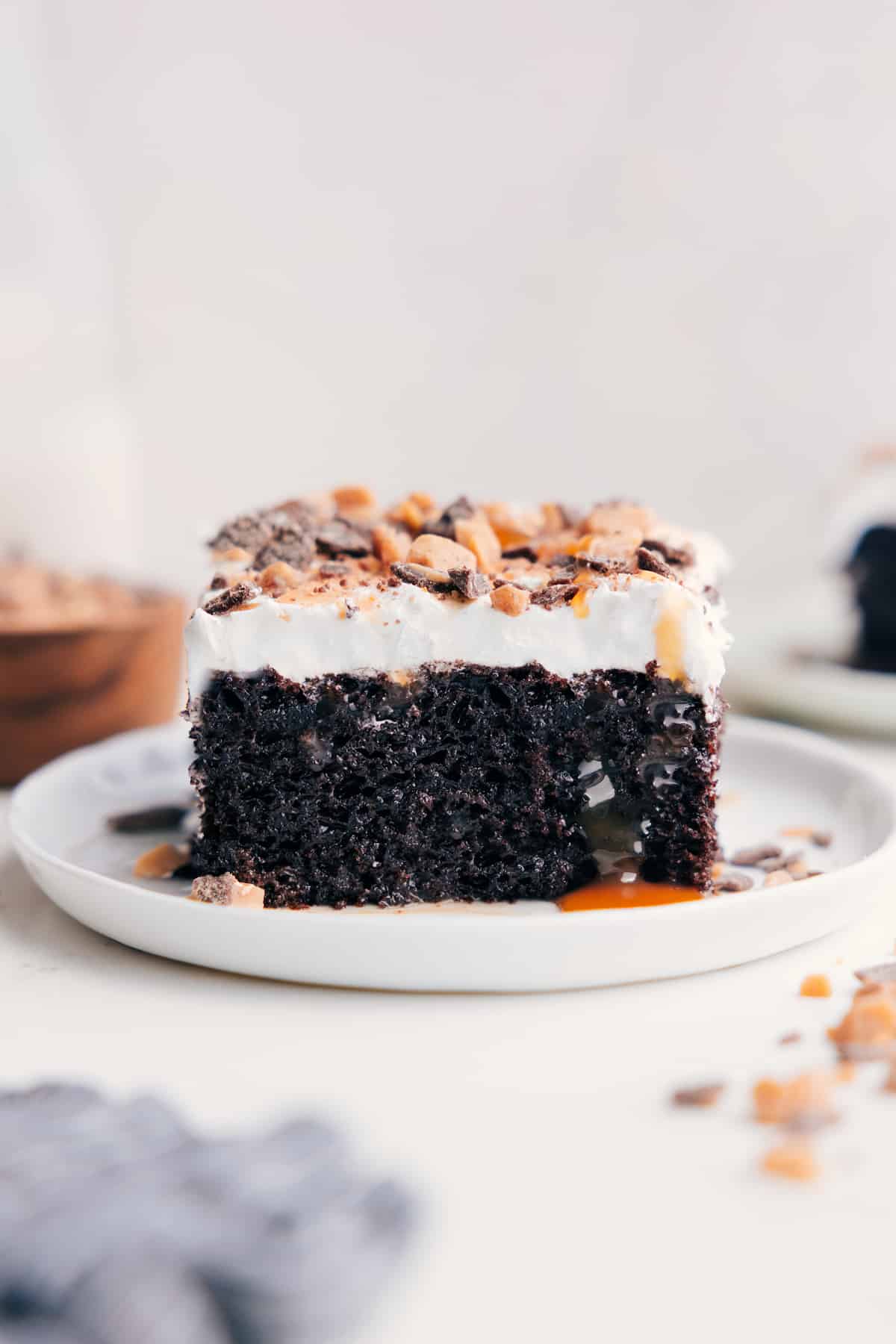 Chocolate Poke Cake on a plate with caramel dripping off the side.