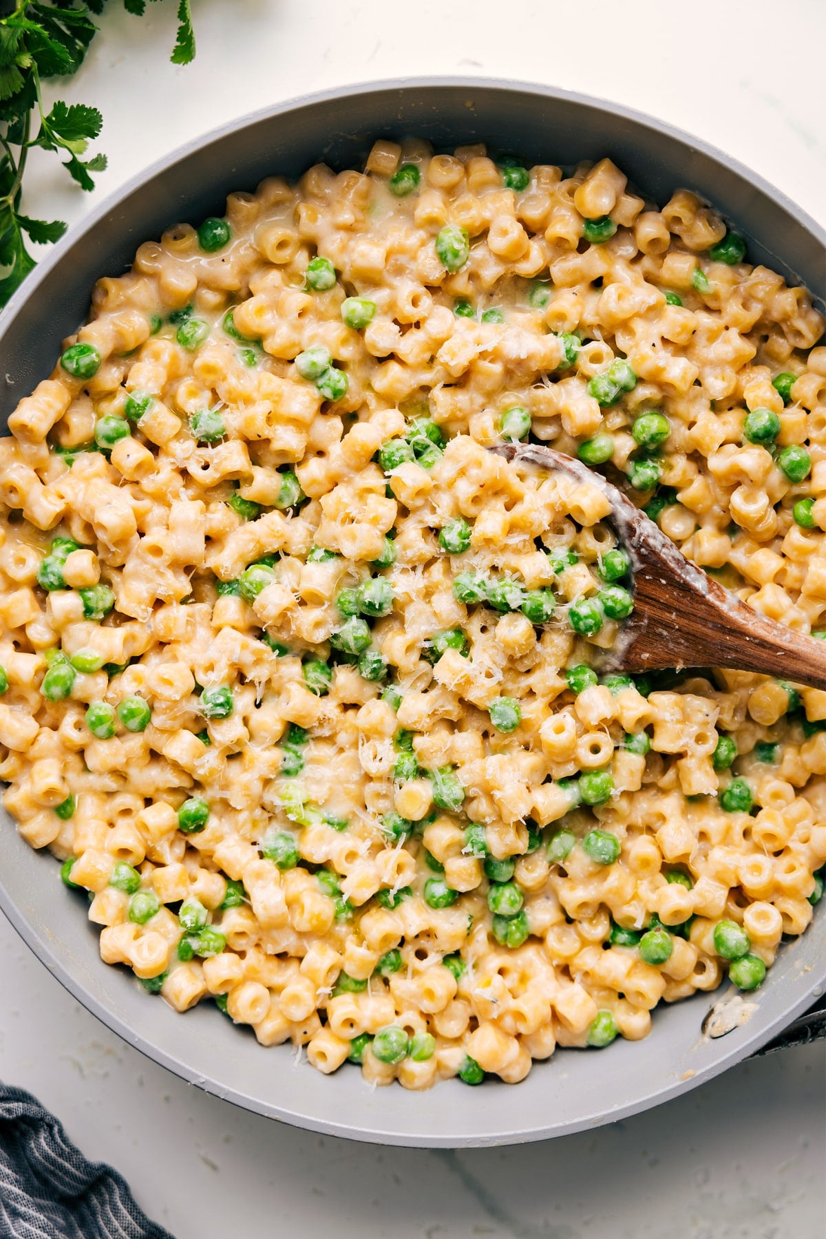 20 Minutes To The Best, Most Family Friendly Pasta With Peas Recipe Pasta with peas in a pot topped with freshly grated cheese.